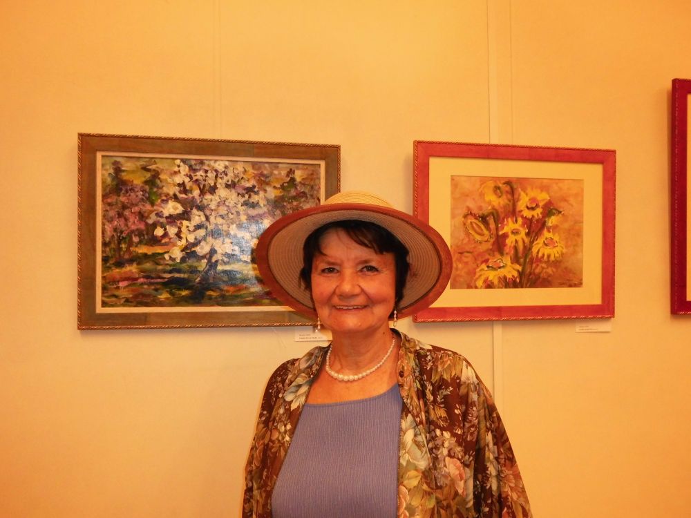 Tarcsányi Ottilia a festményei előtt.jpg